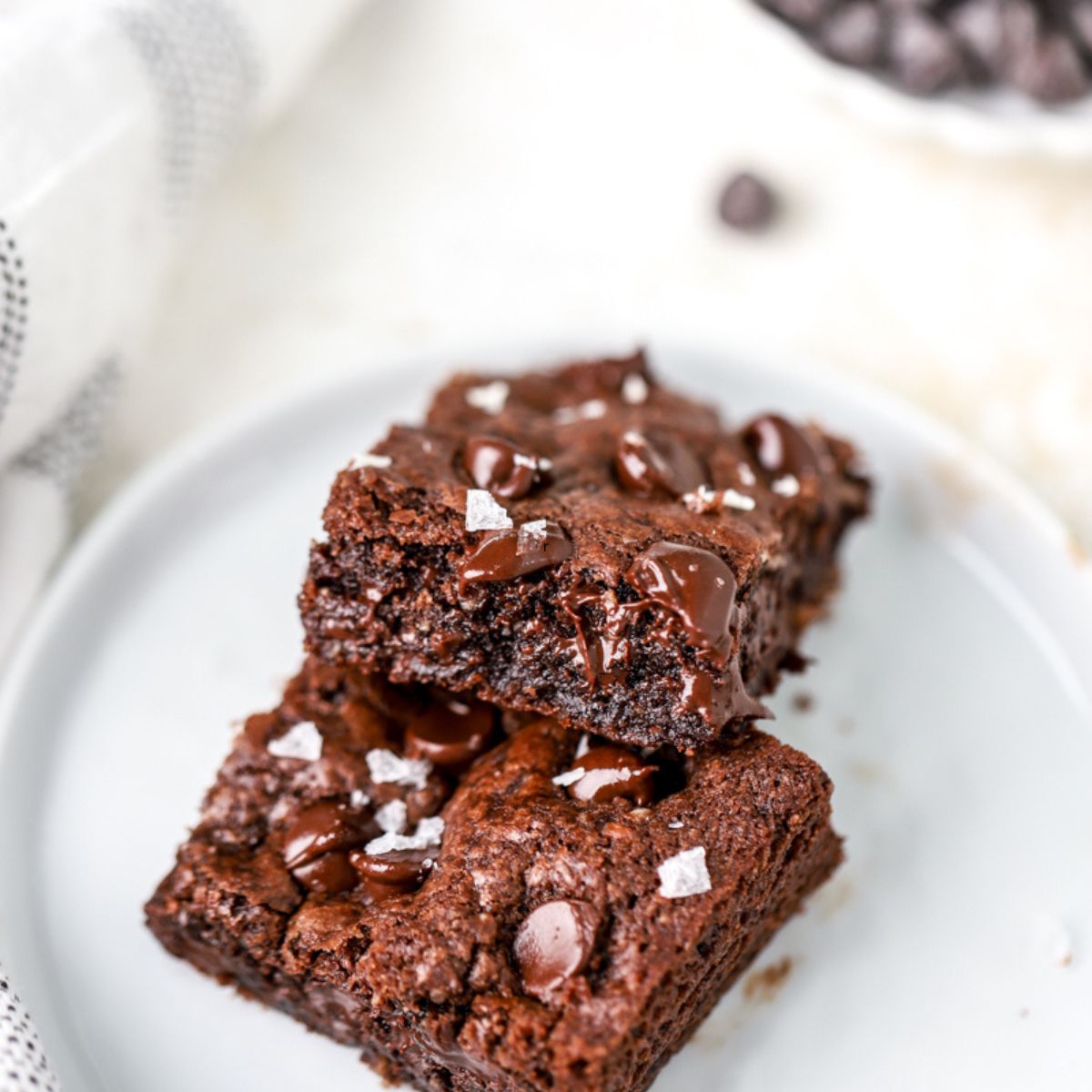 Two chocolate cookie bars topped with chocolate chips on a white plate.