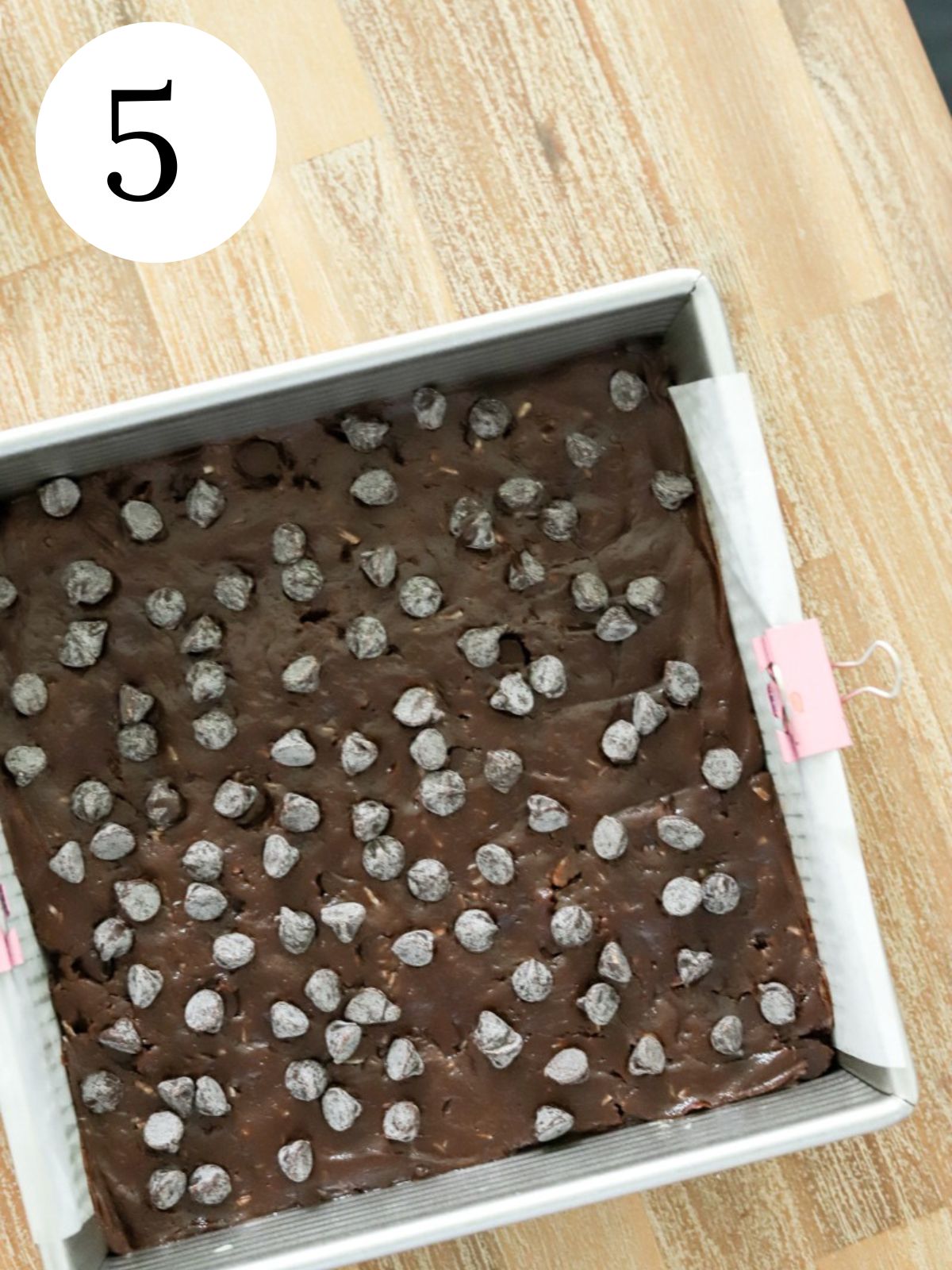 Chocolate dough spread in a pan topped with chocolate chips. 