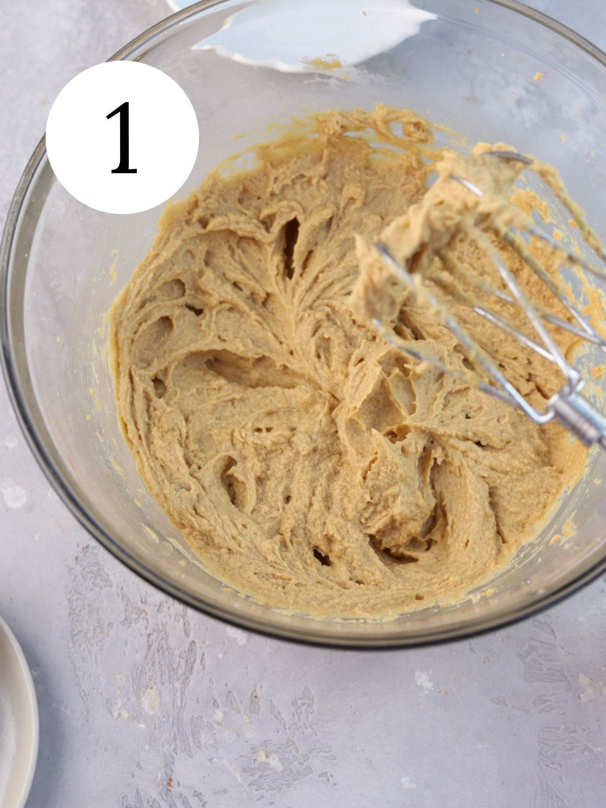 A large mixing bowl with cookie dough and an electric mixer.