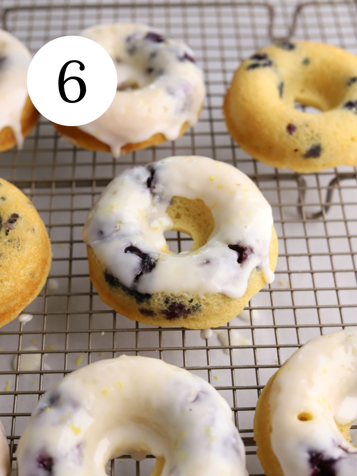A cooling rack with glazed and plain blueberry donuts. 