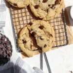 A bowl of chocolate chip cookies and some chocolate chip cookies on a wire rack.