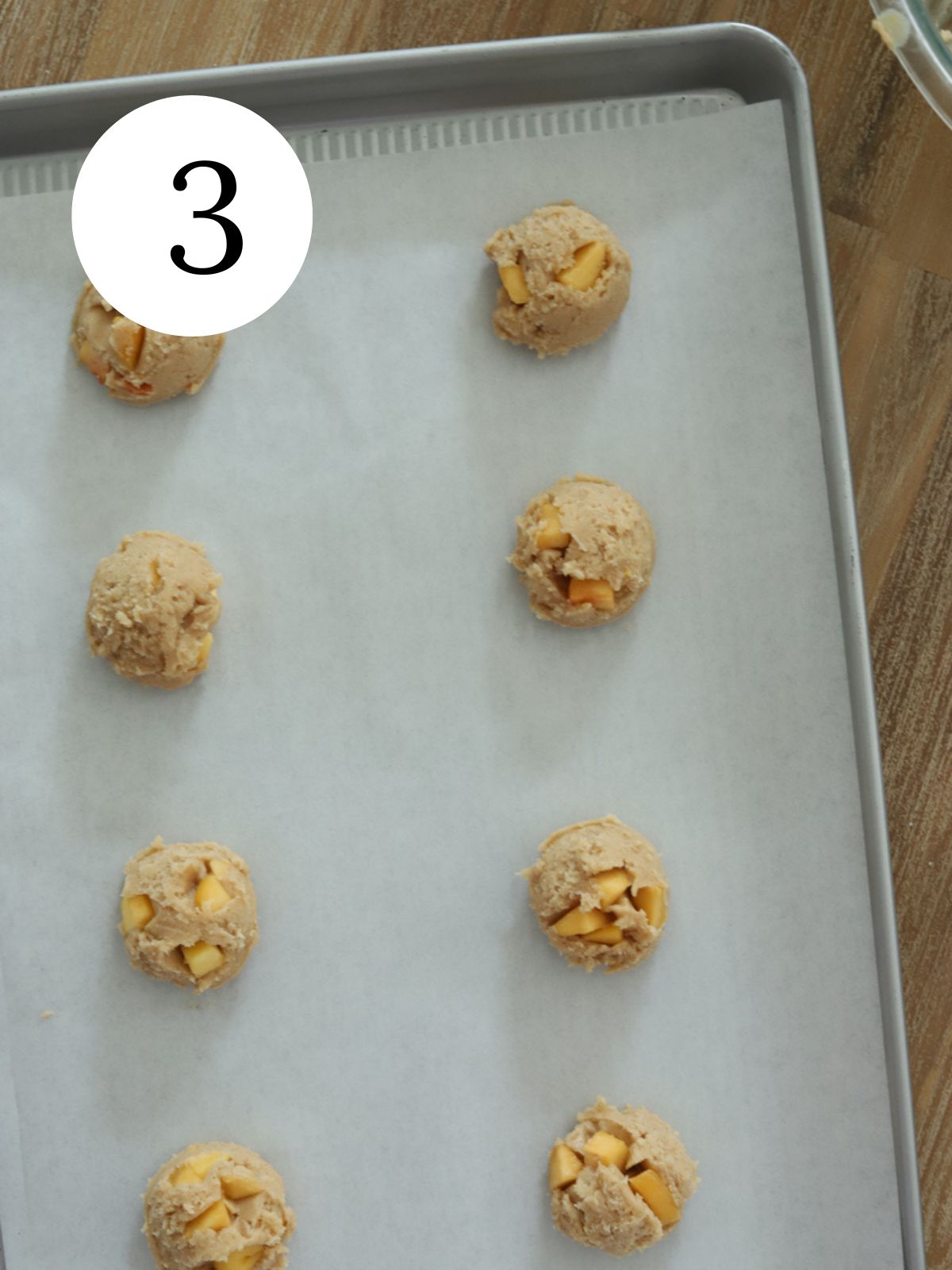 Peach cookie dough balls on a baking sheet lined with parchment paper.