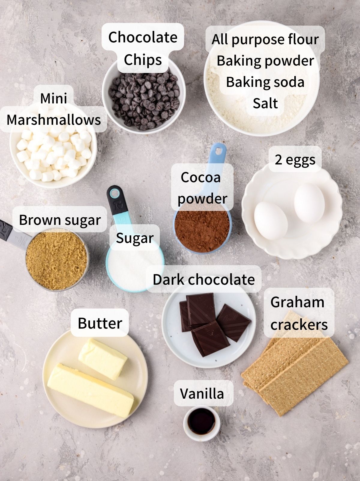 Labeled ingredients needed to make smores cookies laid out on a table.