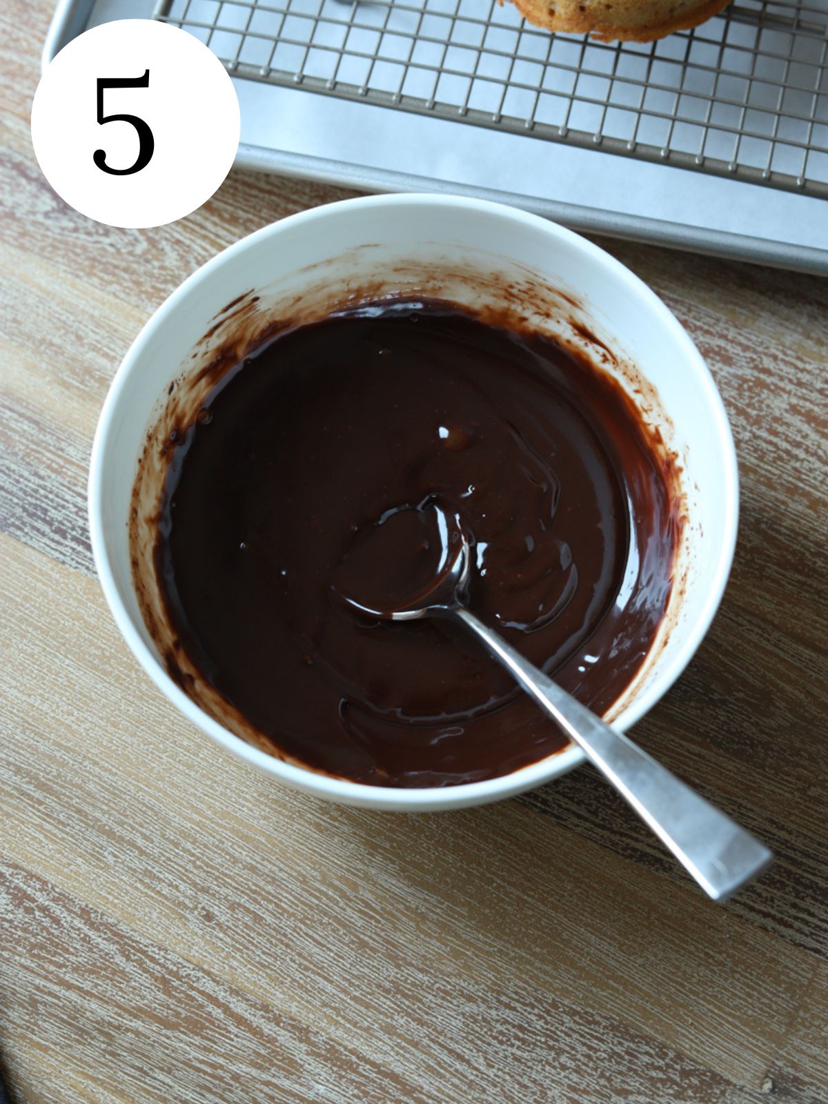 A white bowl with chocolate ganache and a spoon.