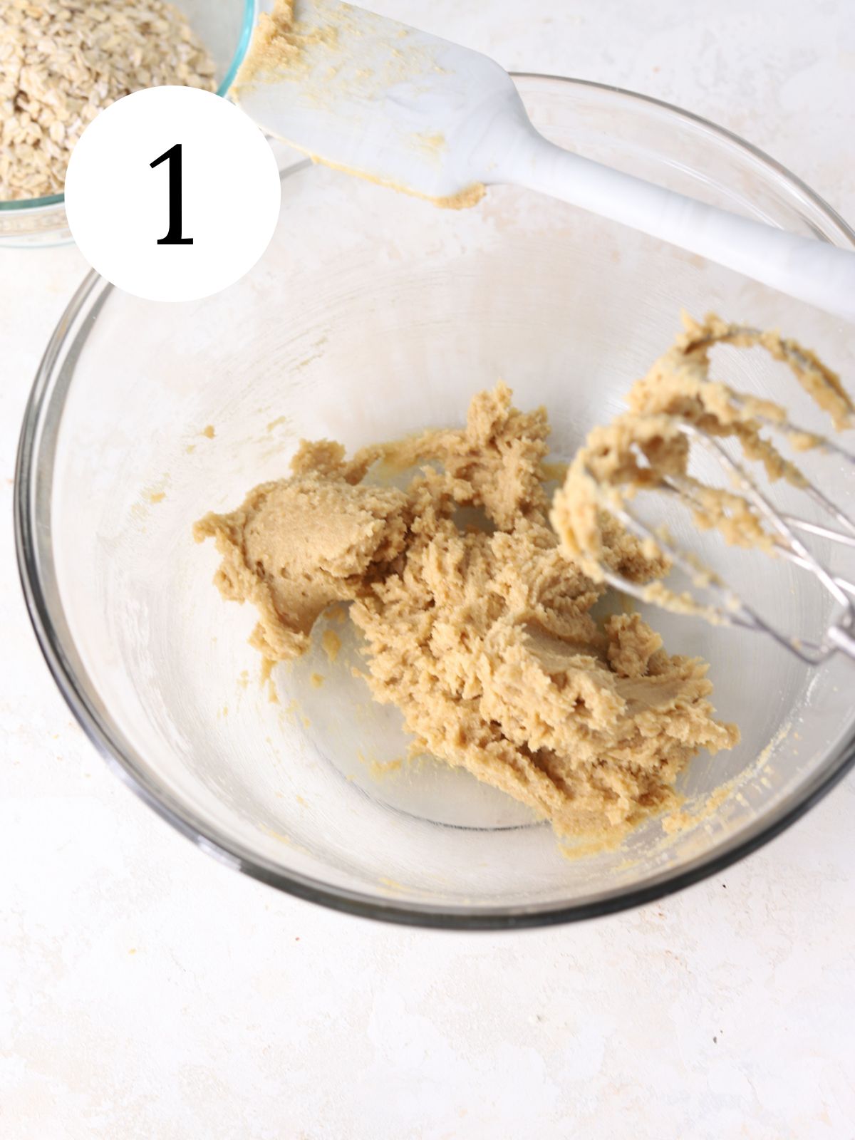 A glass bowl with butter and sugar beaten together with an electric mixer.