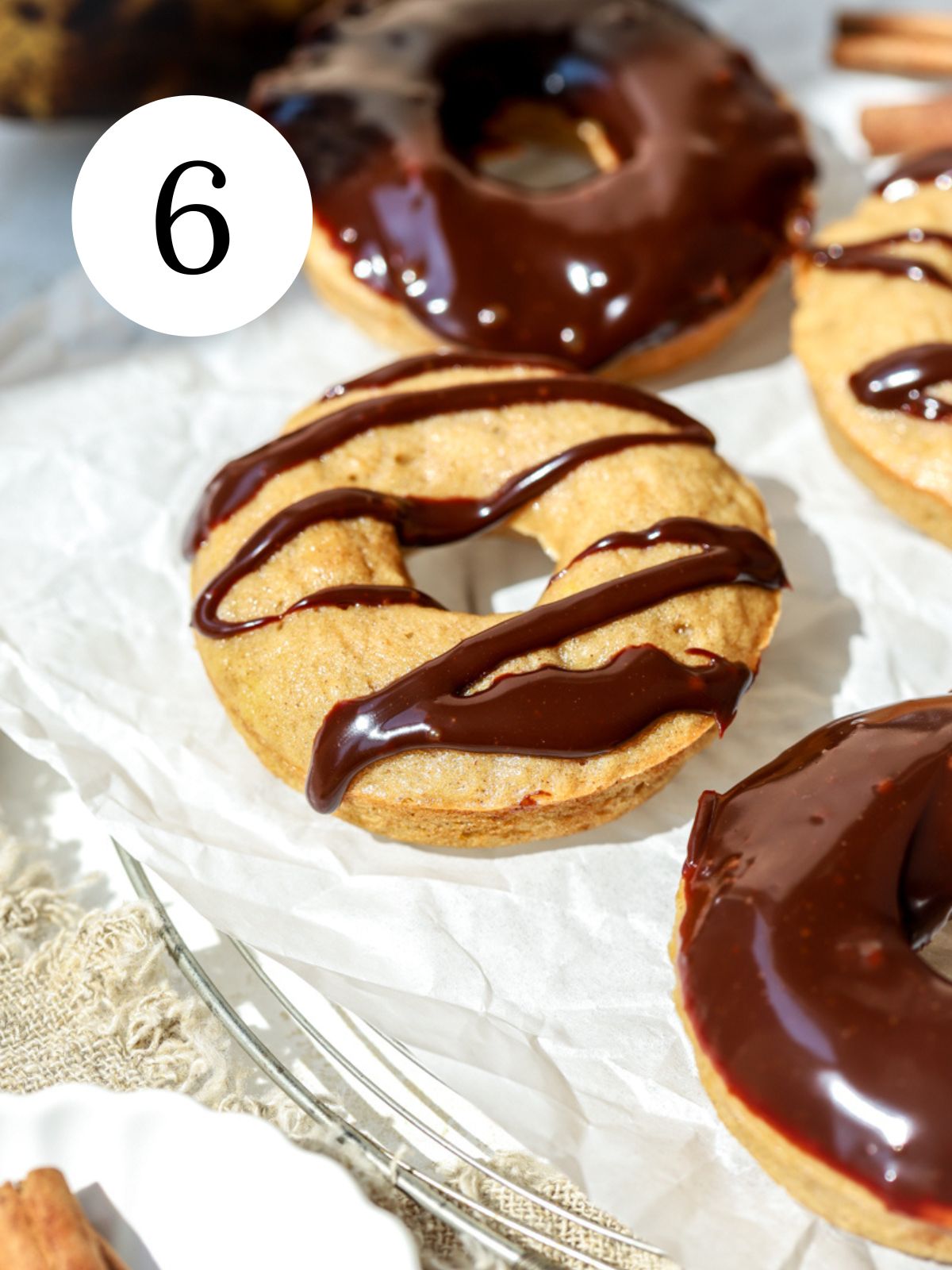 Donuts with chocolate ganache on top on parchment paper.