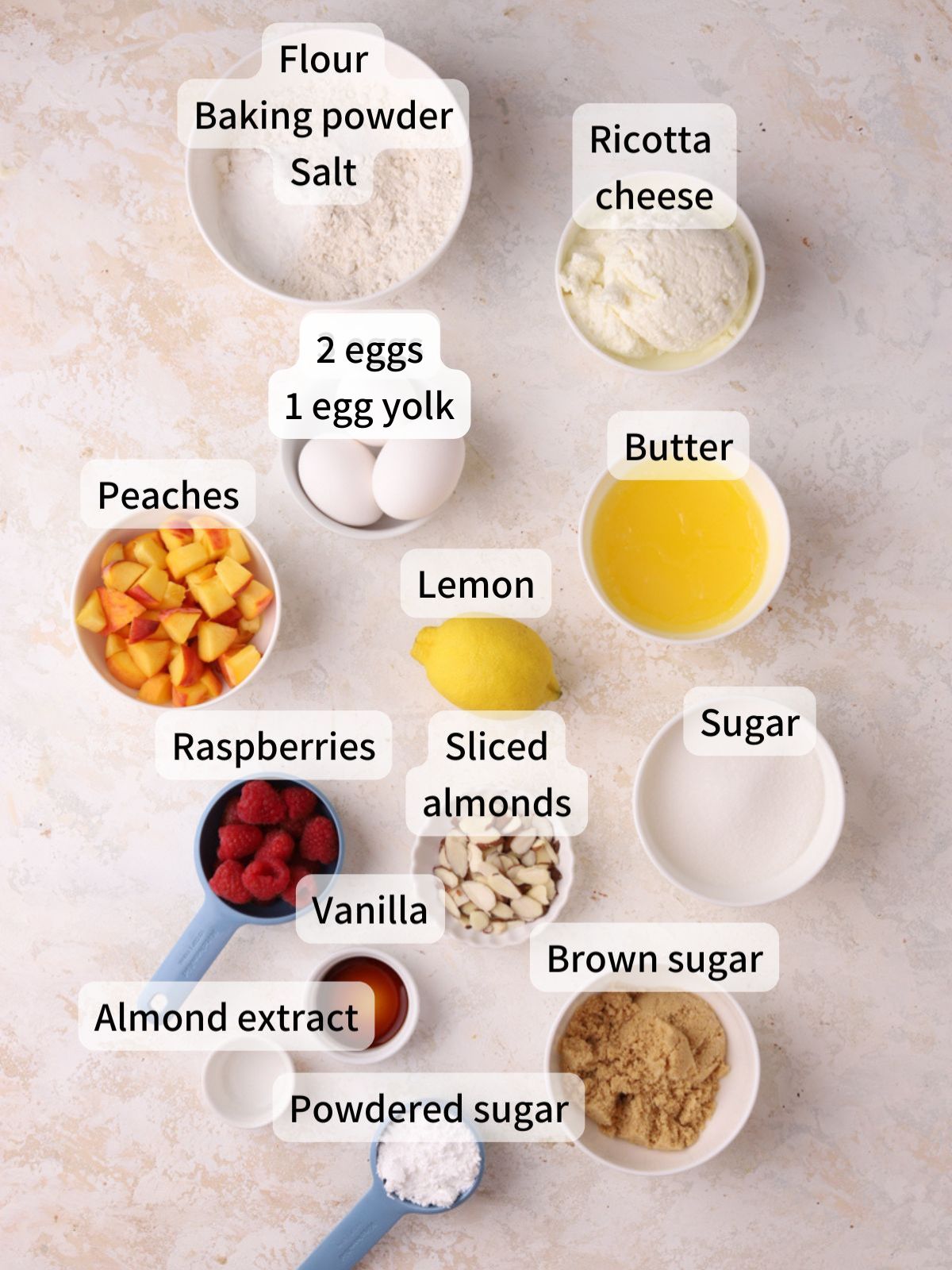 Labeled ingredients needed to make peach raspberry cake laid out on a table.