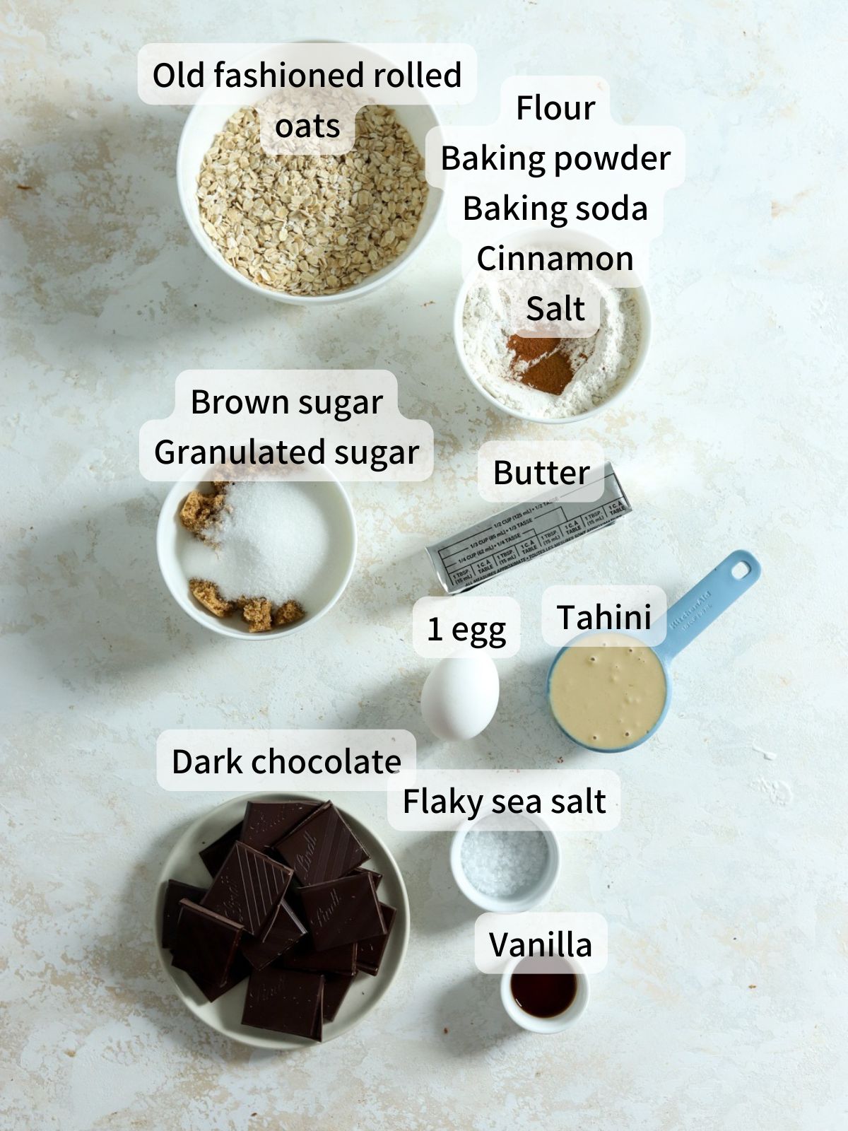 Labeled ingredients needed to make tahini oatmeal cookies laid out on a table.