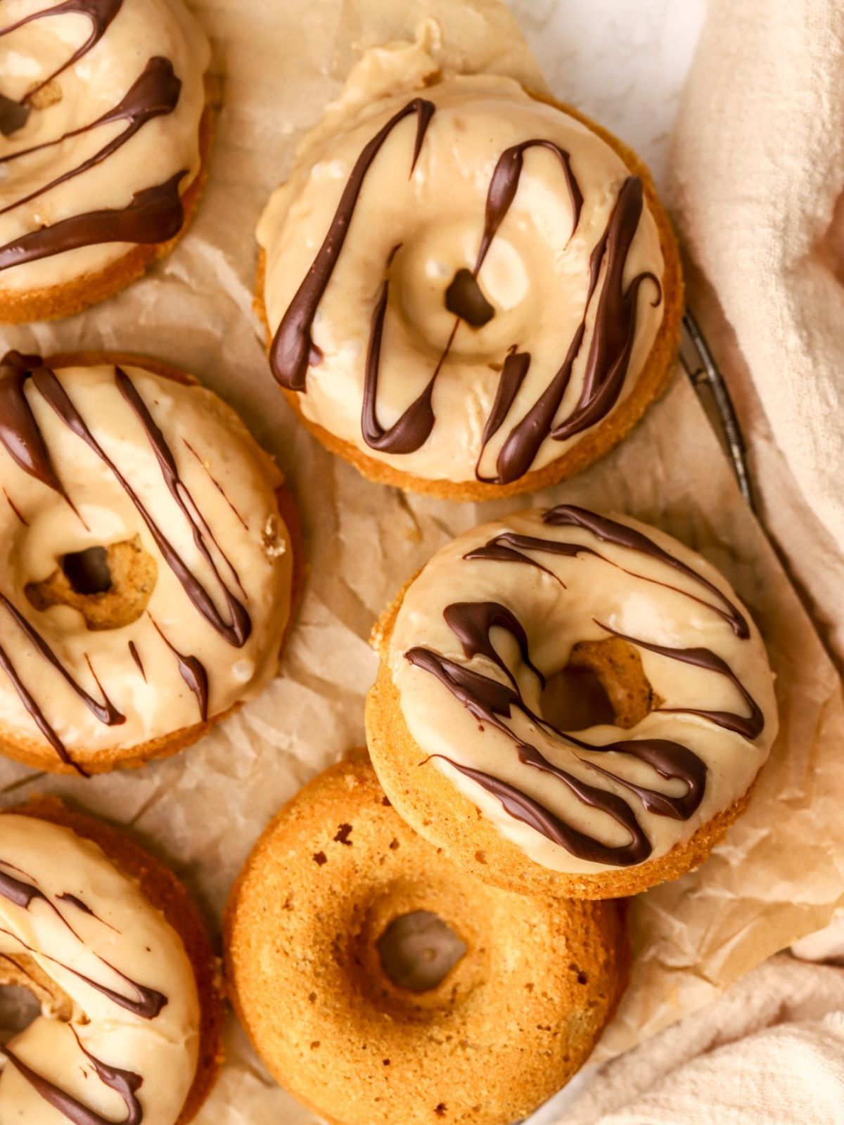 A batch of peanut butter donuts with a peanut butter glaze and drizzled with chocolate.
