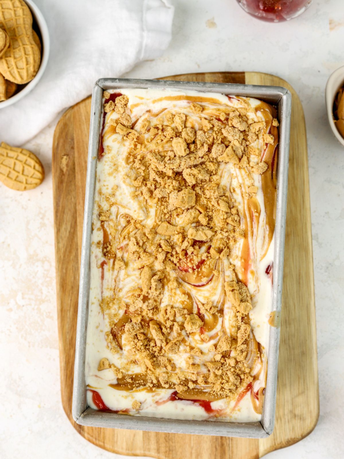 Peanut butter and jelly ice cream with crushed cookies in a loaf pan. 
