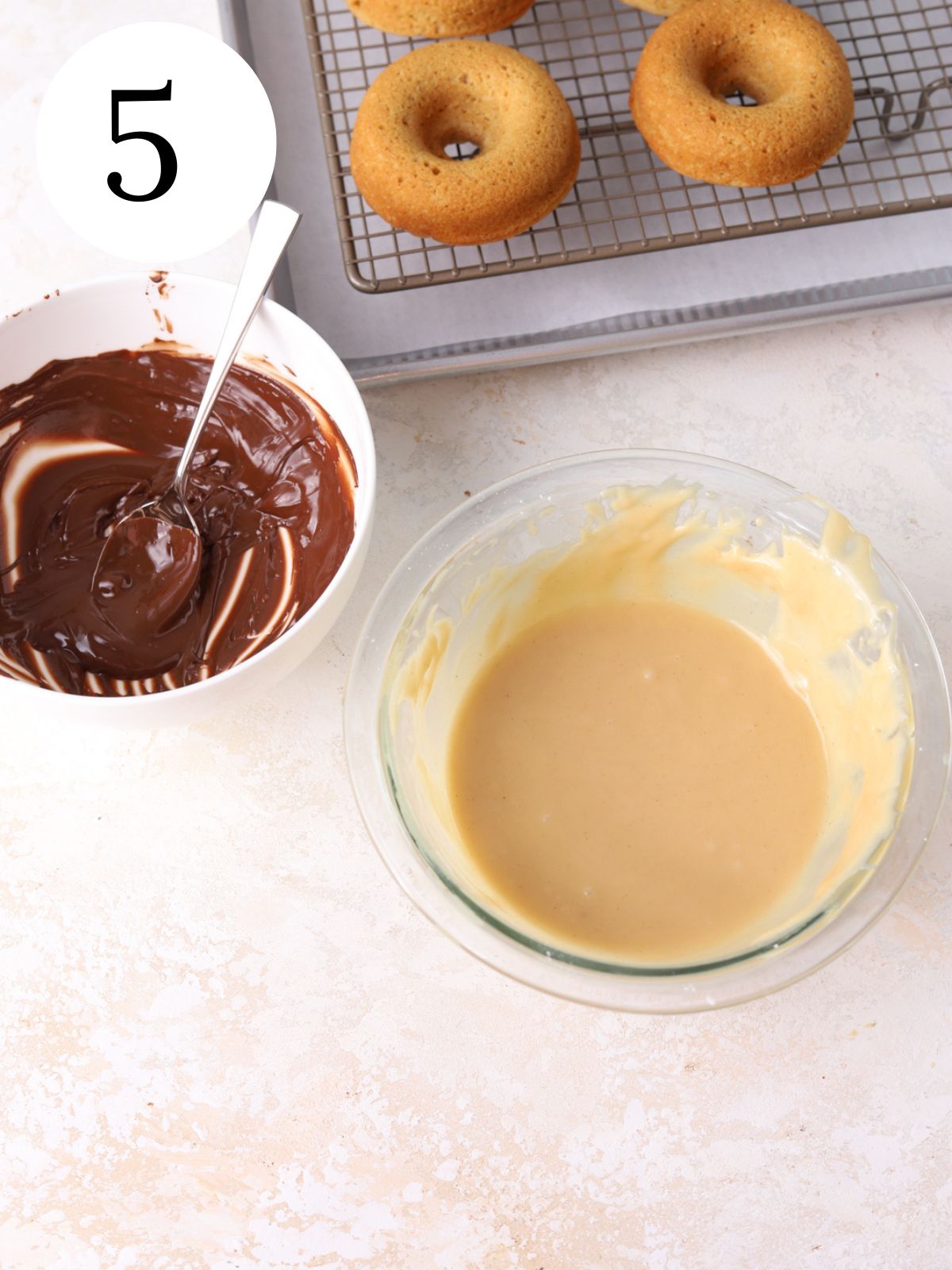 A bowl of peanut butter icing, a bowl of melted chocolate and some donuts.
