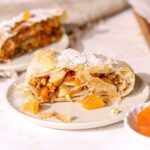 A piece of apricot strudel dusted with powdered sugar on a plate.