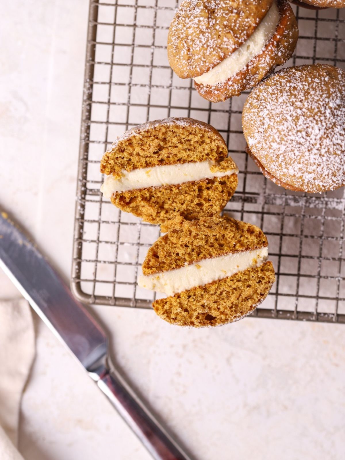 A pumpkin whoopie pie sliced in half on a wire rack.