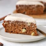 A slice of frosted apple cake on a plate.