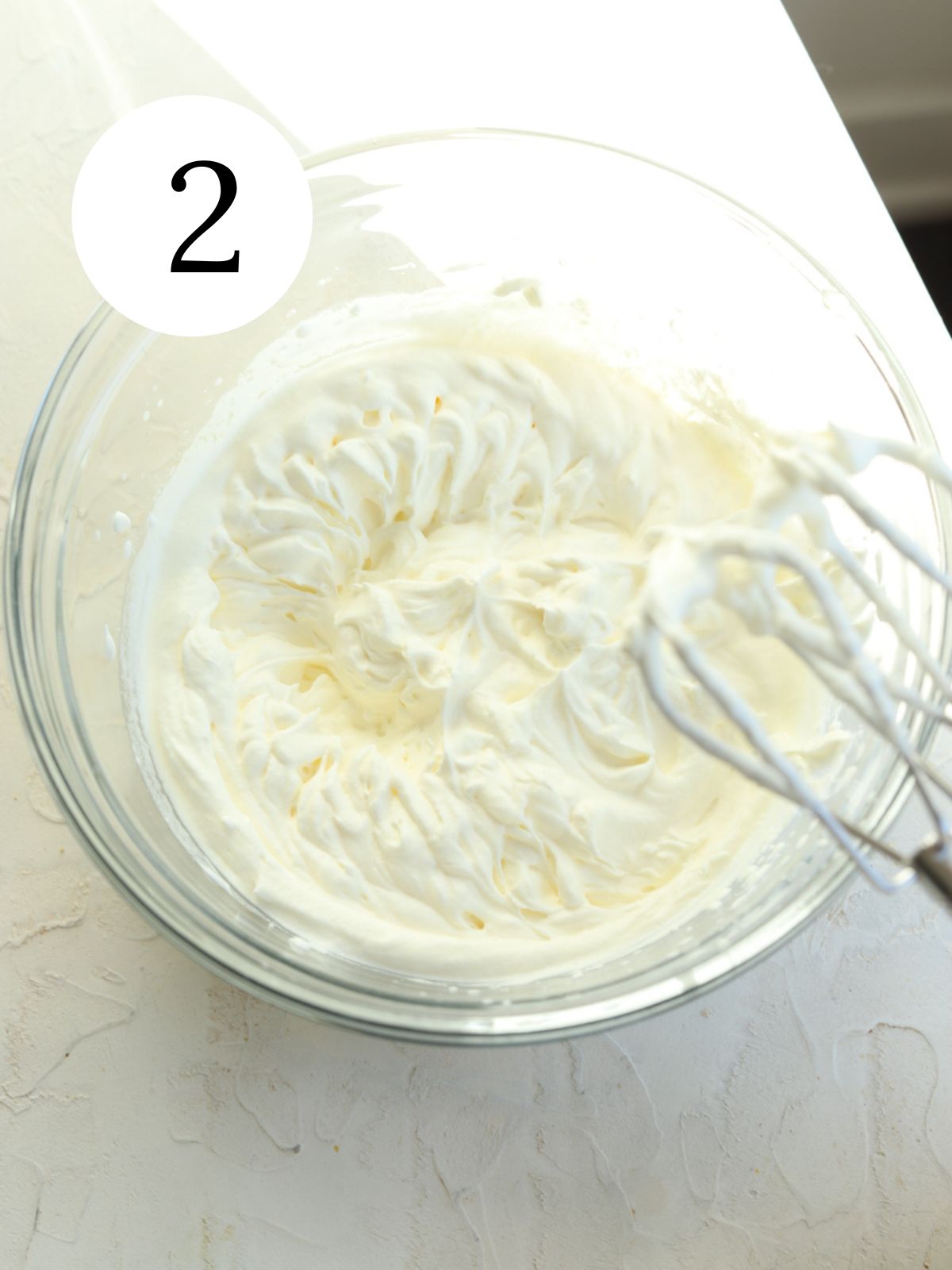 A bowl of whipped cream and a mixer.