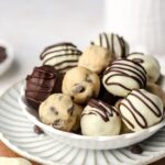 A bowl of chocolate chip cookie dough balls set on a plate.