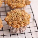 A muffin with streusel topping on a wire rack.