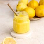 Lemon curd in a jar with a spoon in it.