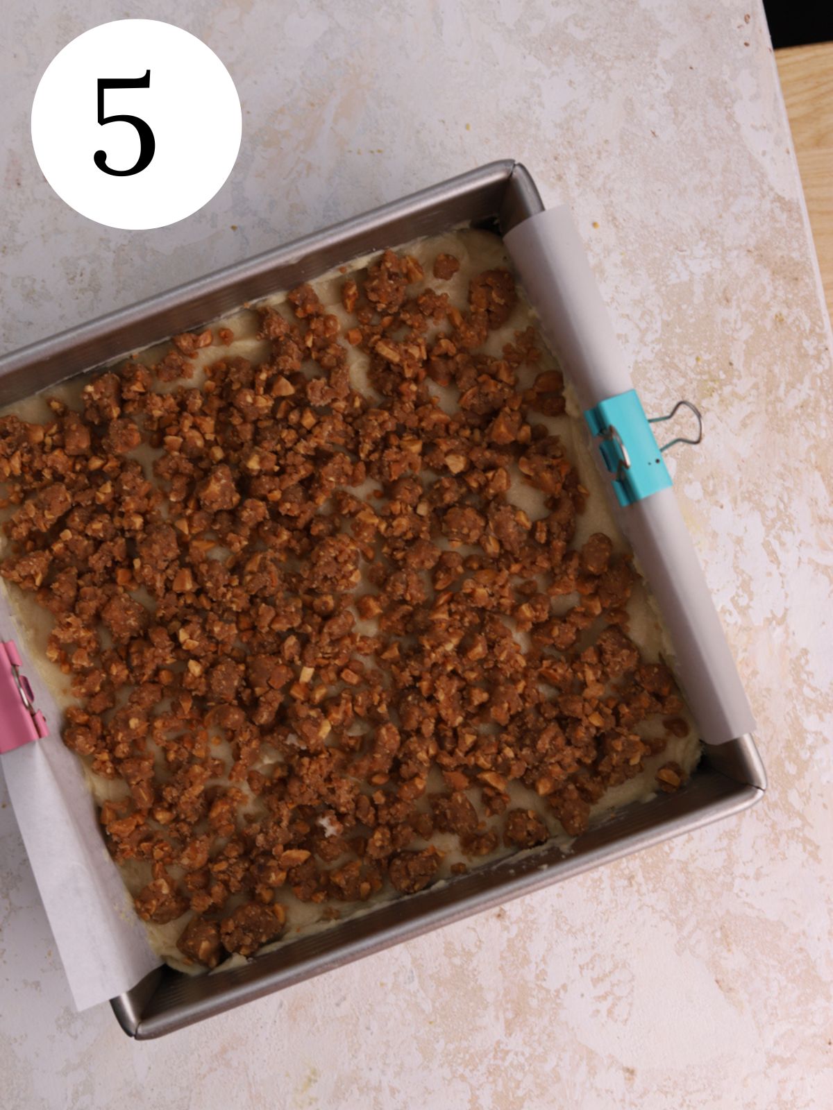 A square pan with cake batter and a crumble topping.