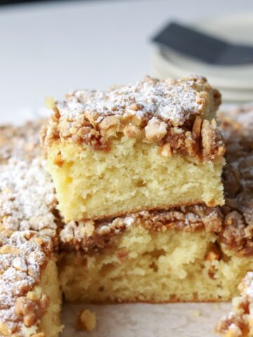 Squares of coffee cake topped with almond streusel and powdered sugar.