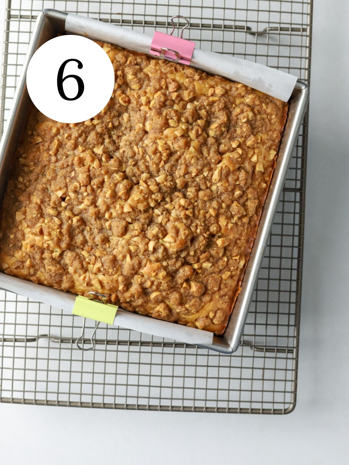 A crumble topped coffee cake in a square pan on a wire rack.
