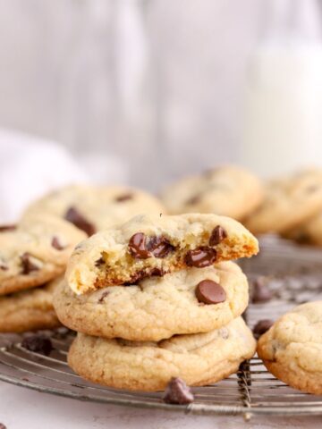 Chocolate chip cookies on a round rack next to some milk.