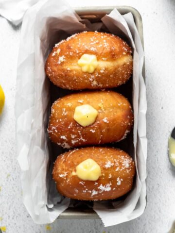Three donuts with a lemon filling in a pan.