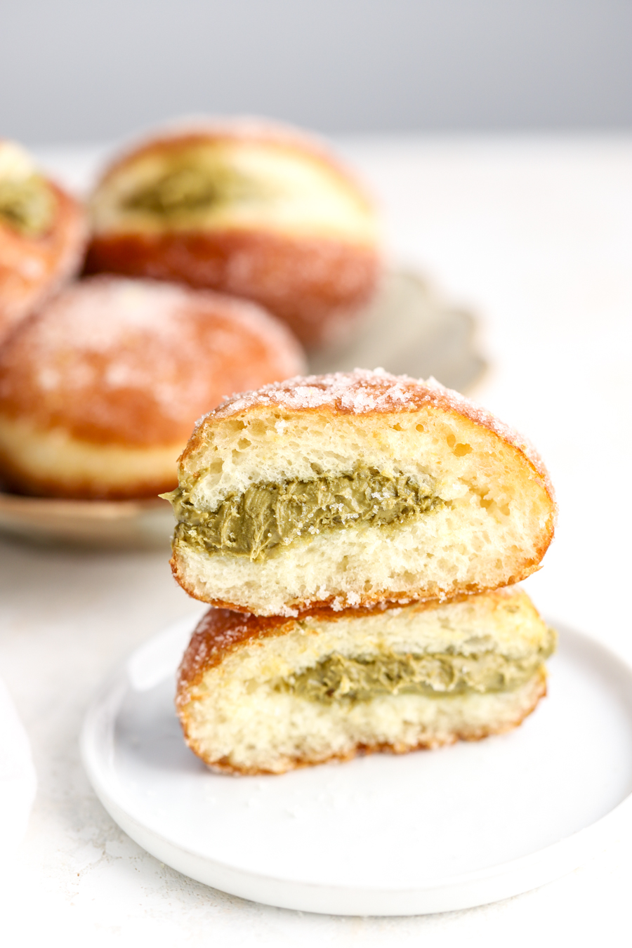 A sugar coated donut cut in half with a pistachio cream filling. 