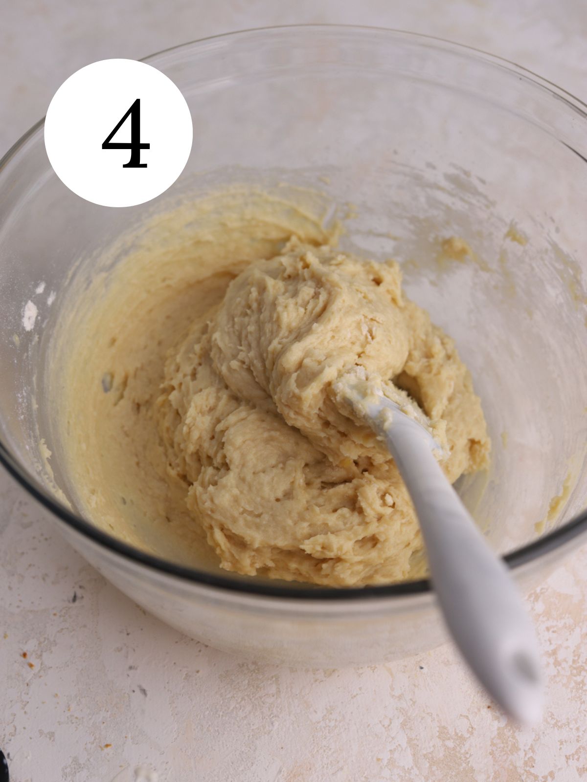A glass mixing bowl with cake batter and a spatula.
