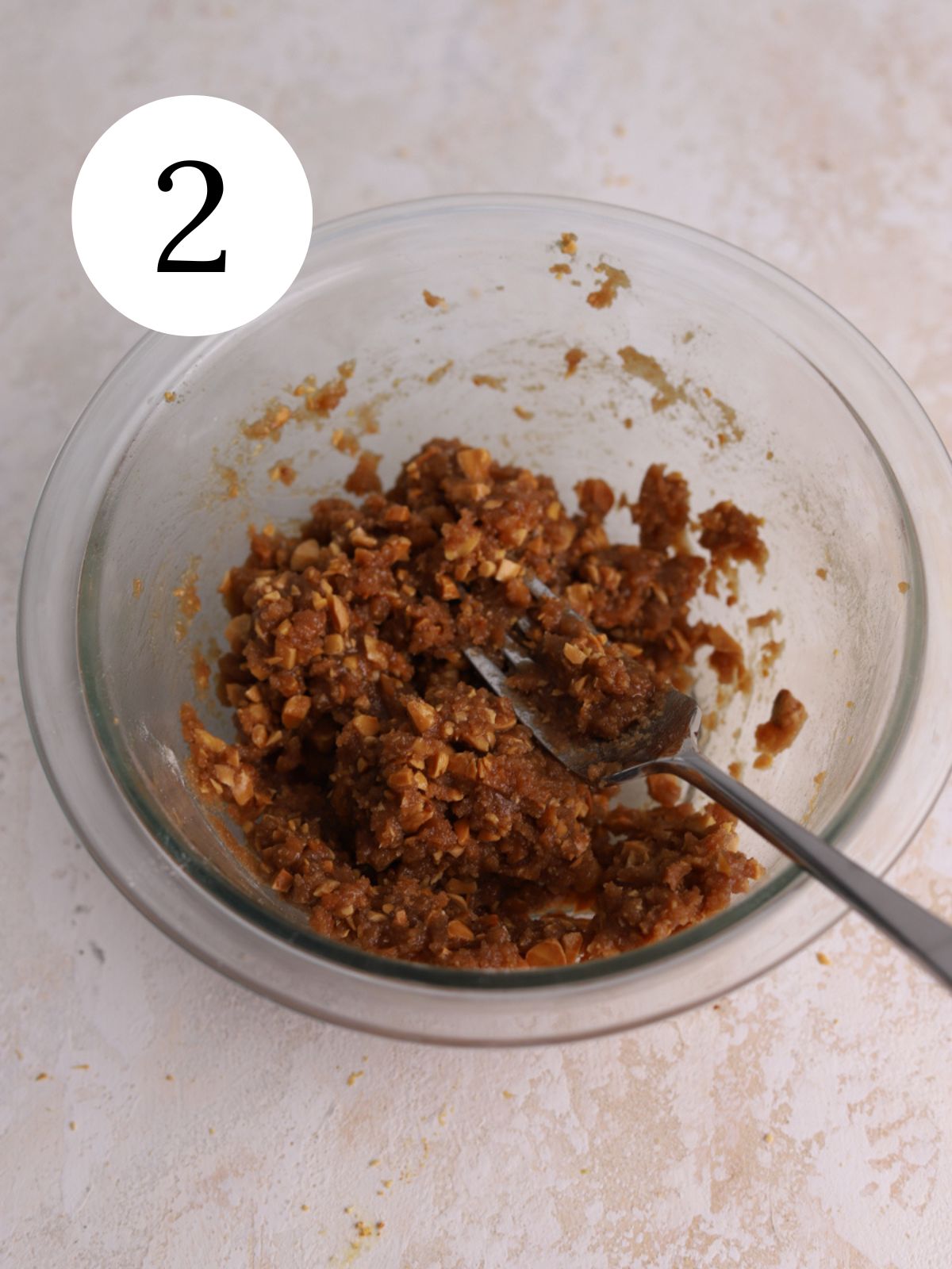 Almond streusel topping stirred together in a glass bowl with a fork.