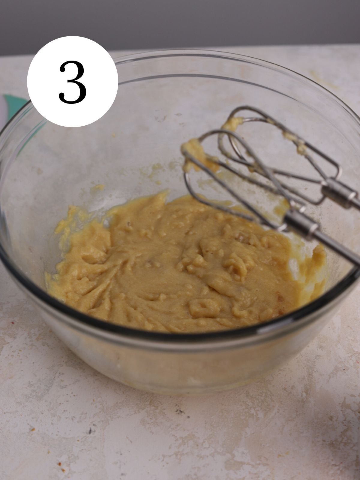 Wet ingredients mixed together in a glass bowl with an electric mixer.