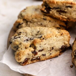 A golden brown scone with dates on parchment paper.