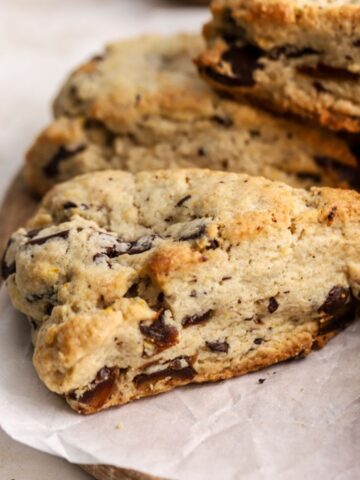 A golden brown scone with dates on parchment paper.