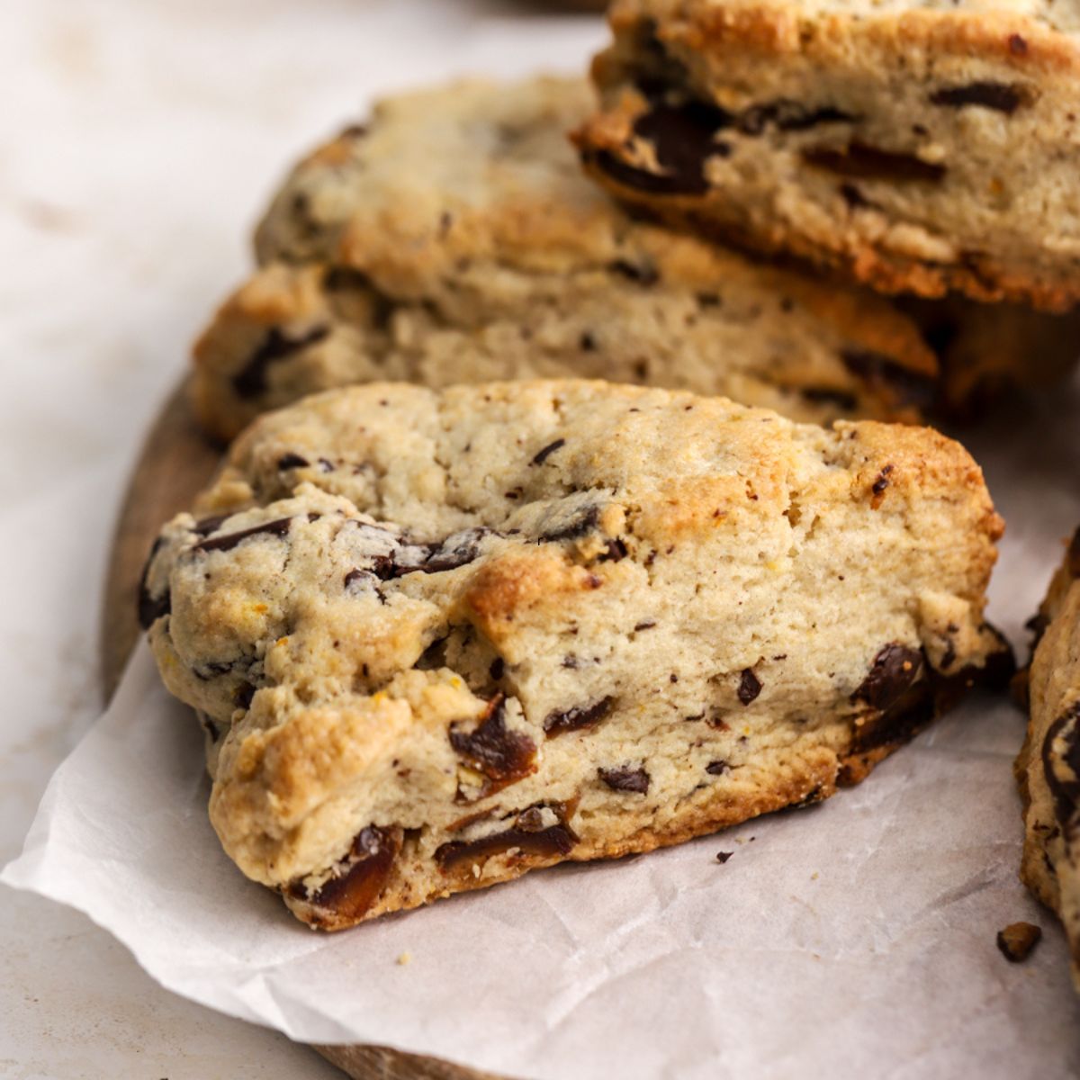 A golden brown scone with dates on parchment paper.