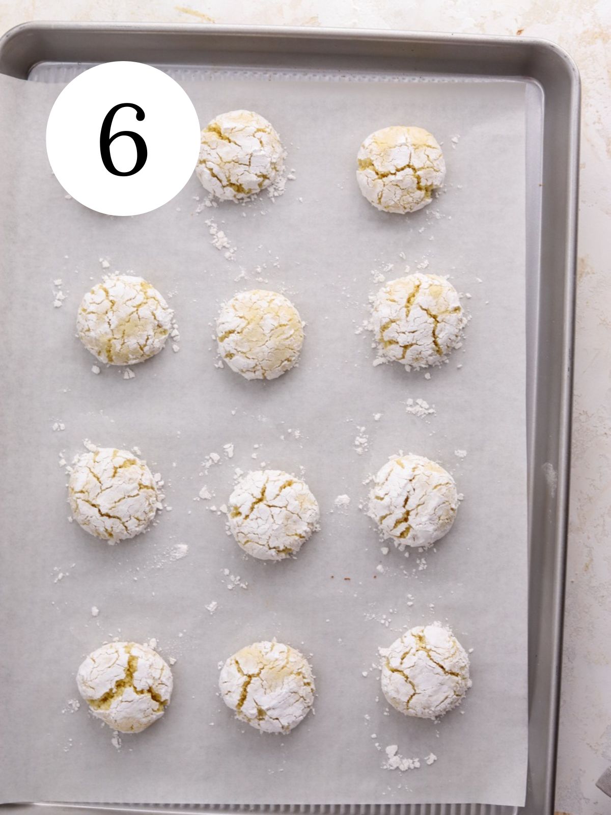 A baking sheet with a batch of cookies coated with powdered sugar. 