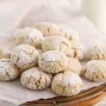 A batch of cookies coated with powdered sugar on parchment paper.