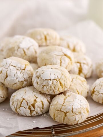 A batch of cookies coated with powdered sugar on parchment paper.