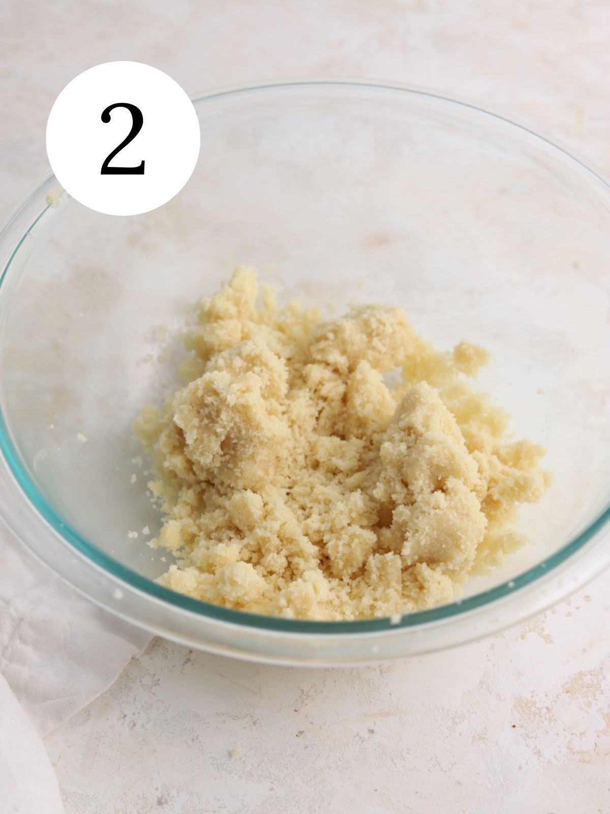 A glass bowl with almond flour mixed together with butter. 