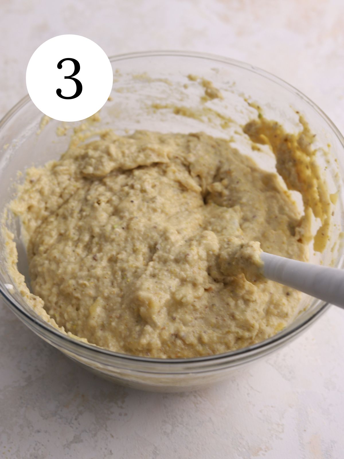A large mixing bowl with banana bread batter and a spatula.