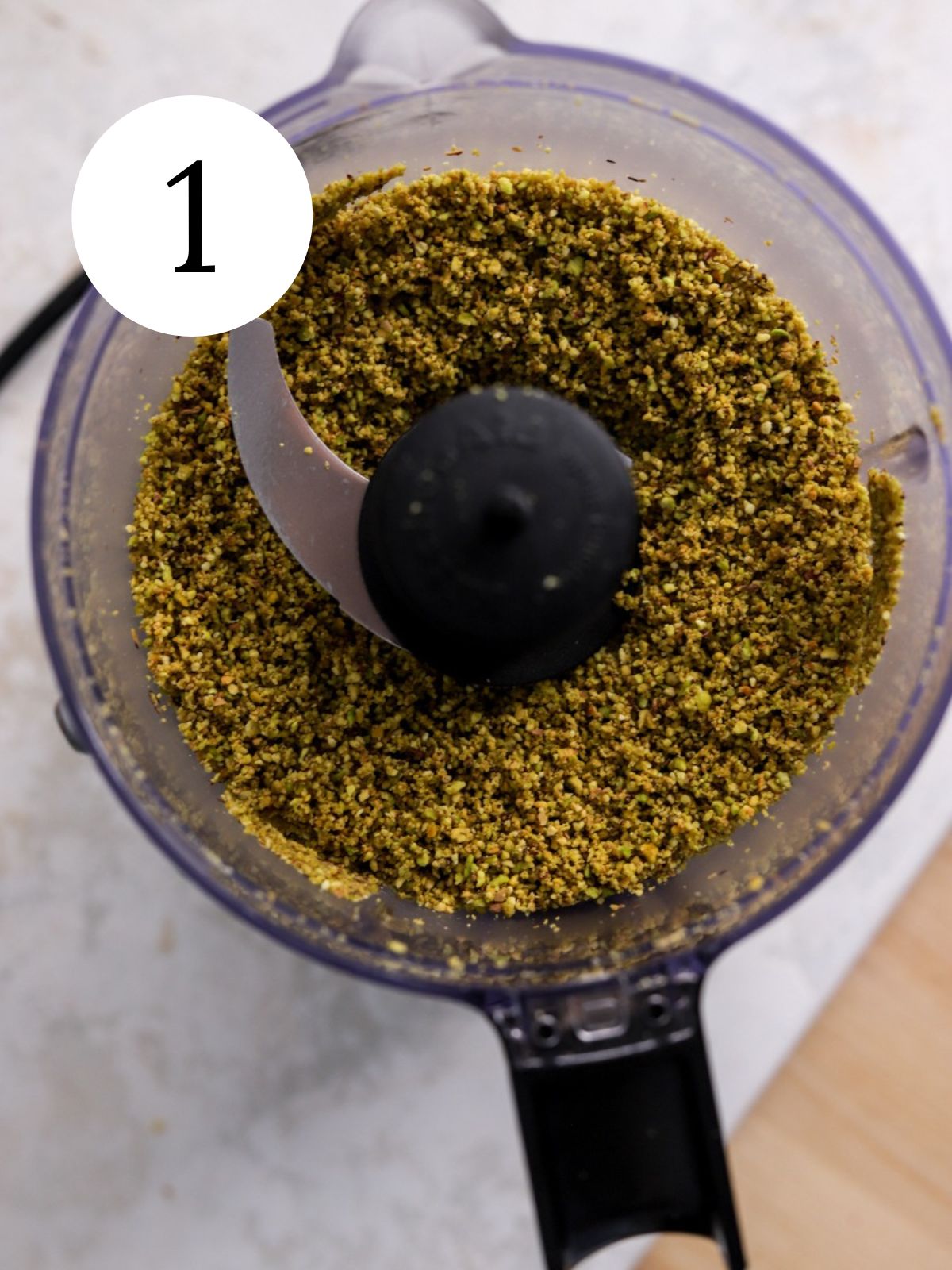 A food processor with finely ground pistachios.