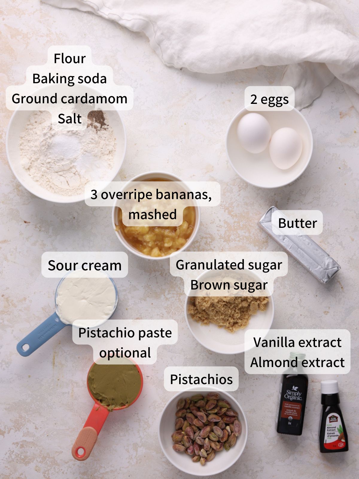 Labeled ingredients for banana pistachio bread laid out on a table.