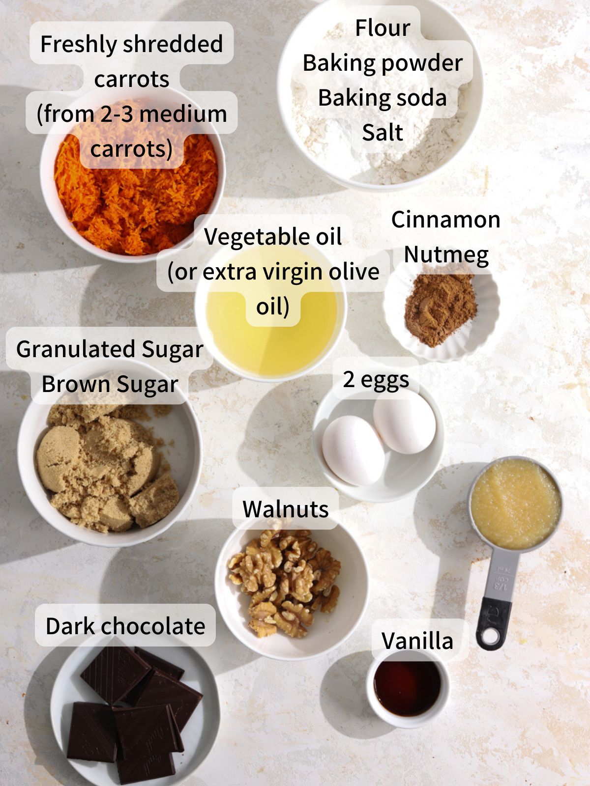 Labeled ingredients needed to make carrot muffins laid out on a table.