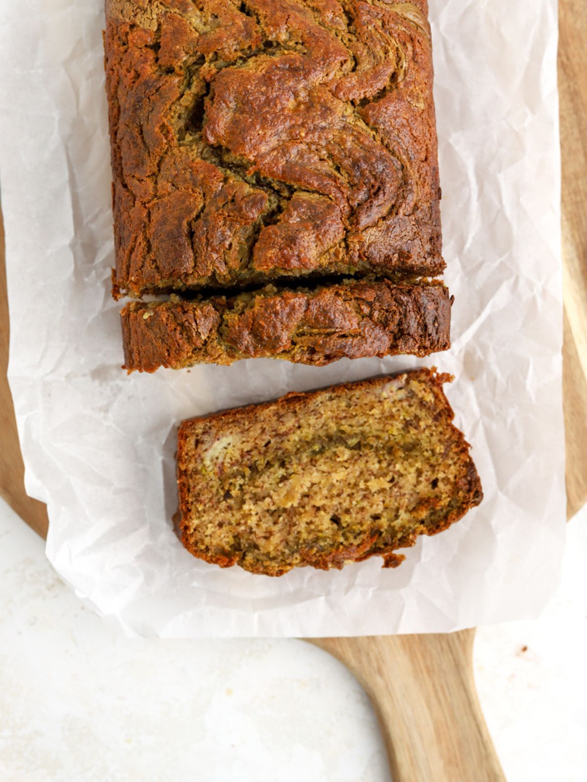 A loaf of banana bread being sliced on parchment paper.