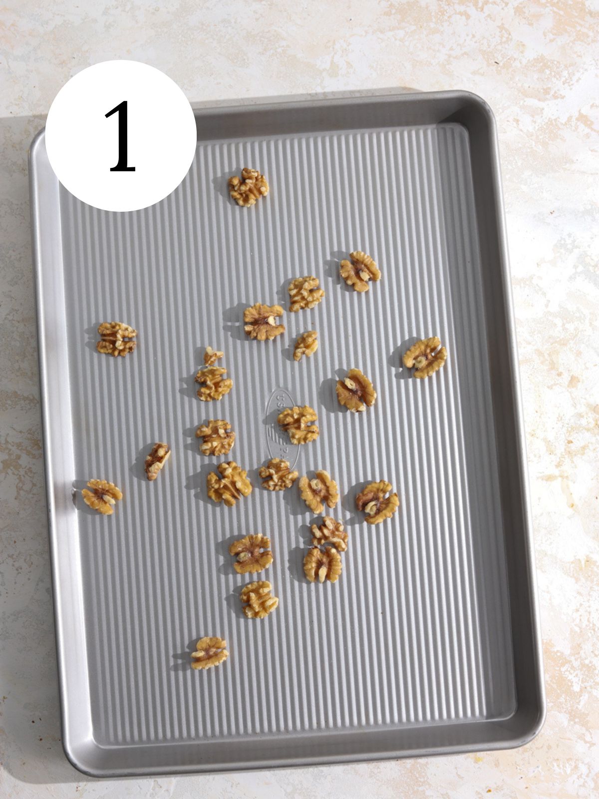 Walnuts spread out on a baking sheet.