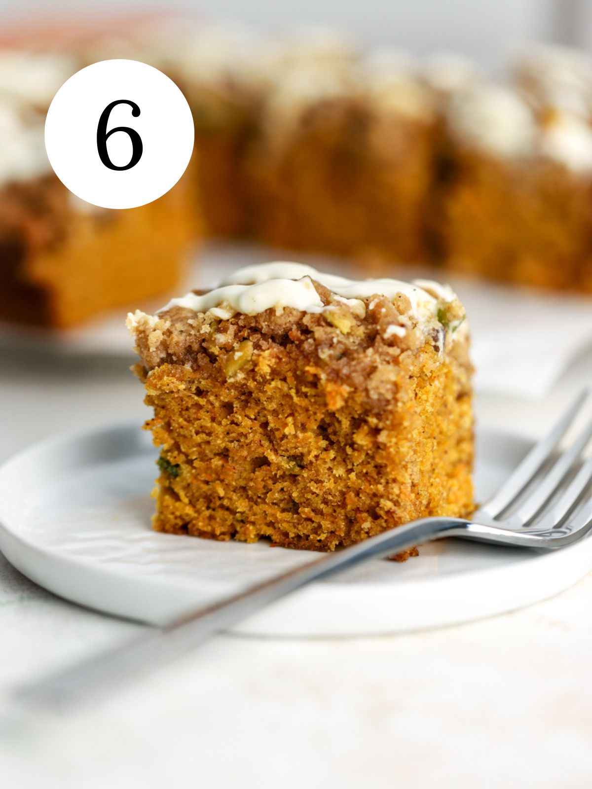 A piece of carrot coffee cake with cream cheese icing drizzled on top.