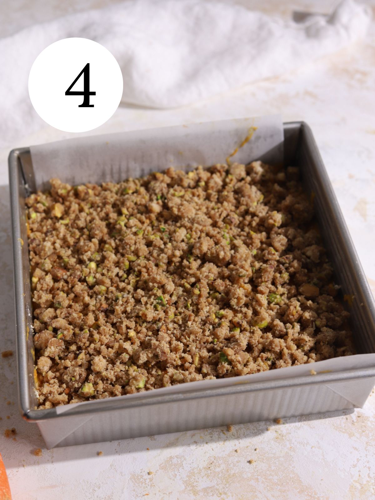 A square cake pan with cake batter and a streusel topping.