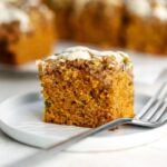 A piece of carrot coffee cake on a plate with a fork.