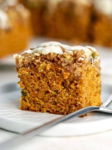A piece of carrot coffee cake on a plate with a fork.