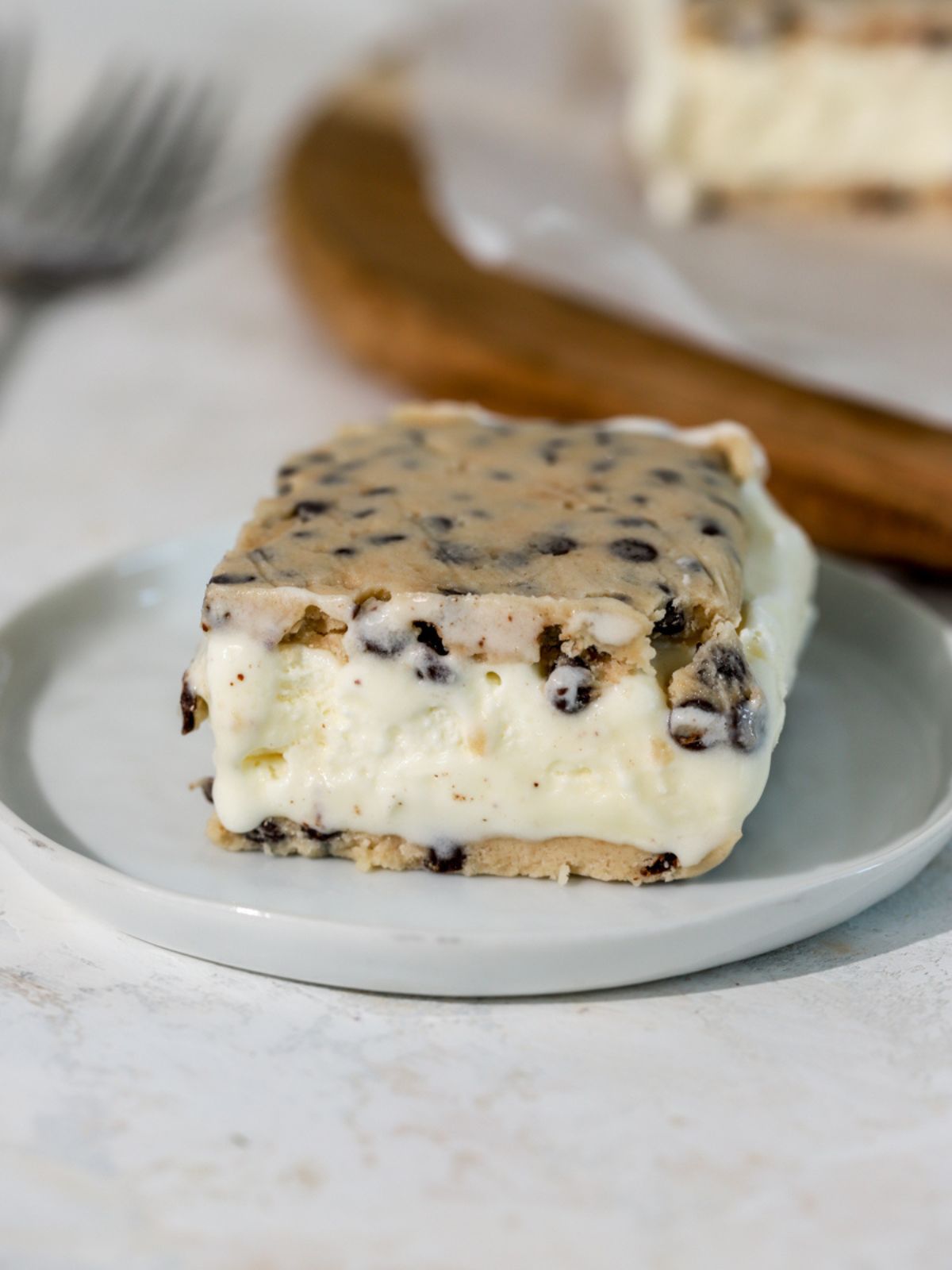 A cookie dough ice cream sandwich on a small white plate. 