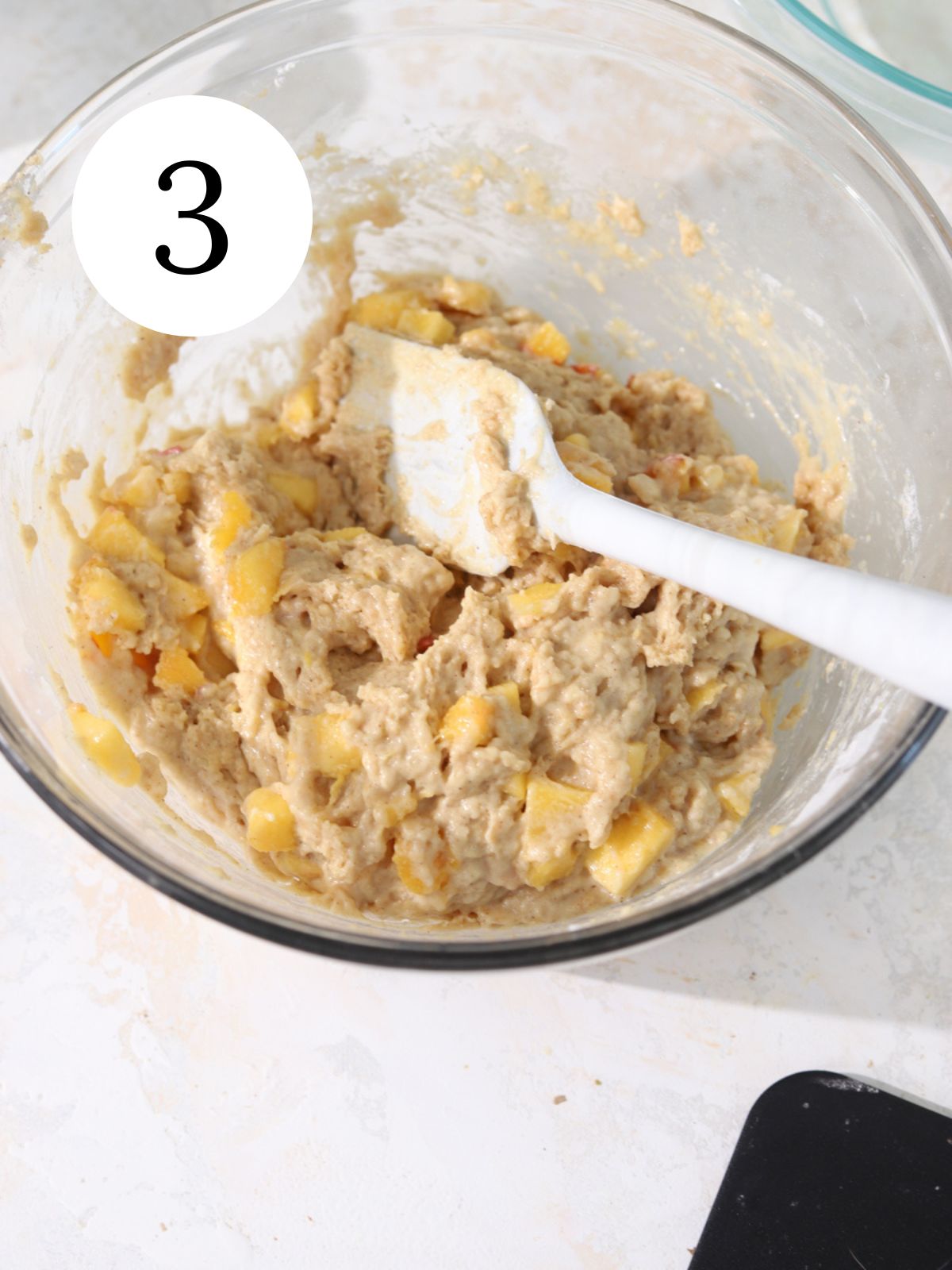 Peaches stirred into batter with a spatula. 